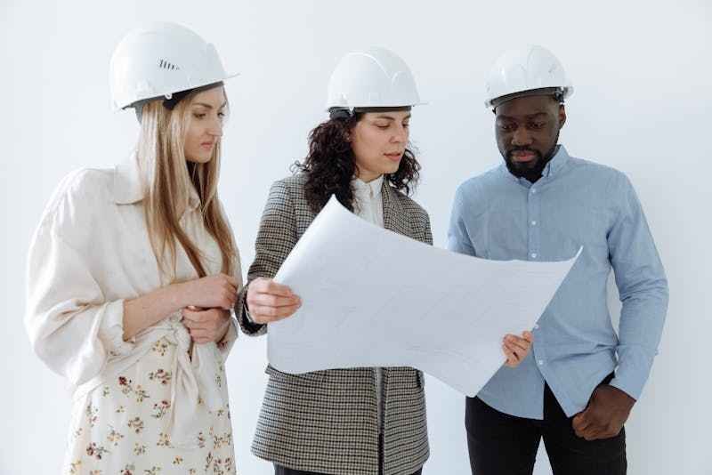 investisseurs immobiliers investisseurs immobiliers, des gens avec un casque blanc sur un chantier discute en tenant un plan